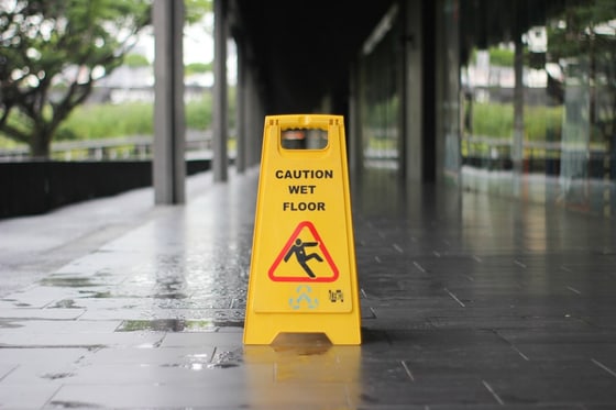 Wet floor with a caution cone in a retail corridor