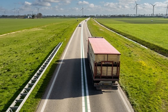 Commercial truck traveling along an open highway through farmland